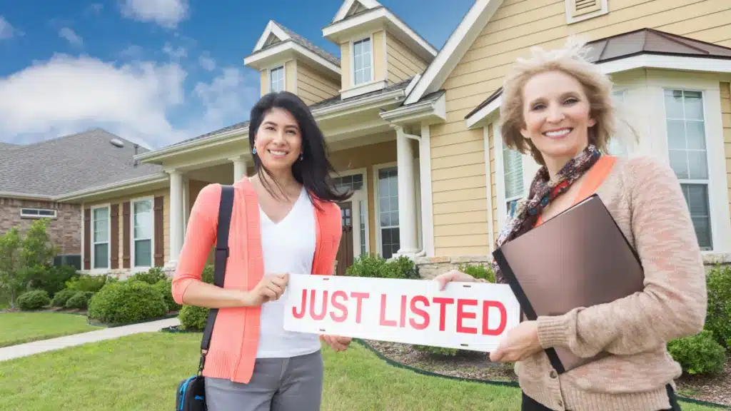 real estate agent and home seller holding a just listed sign